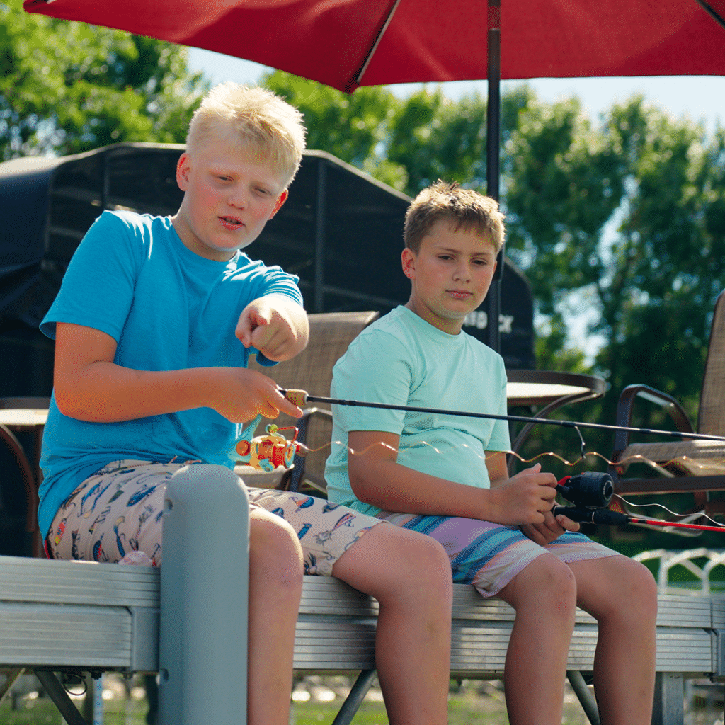 Two boys fishing from a Porta-Dock dock under a red umbrella, from a brand video by Moxie Creative